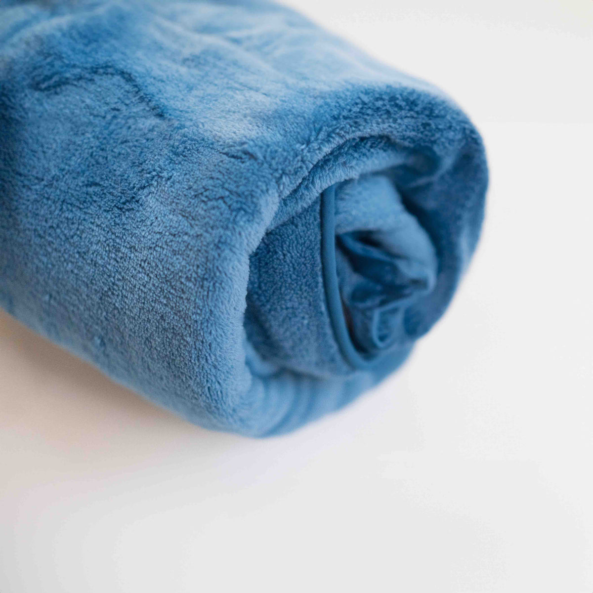 蓝色 Ocean Breeze Dog Towel Robe 卷成小巧的一束。